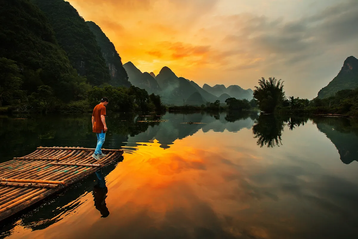 A bamboo raft on the calm Yulong River among karst hills near Yangshuo