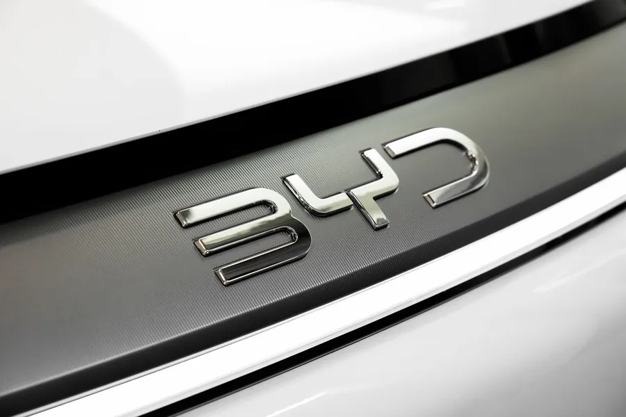 Close-up of a chrome BYD badge on the body of a white car