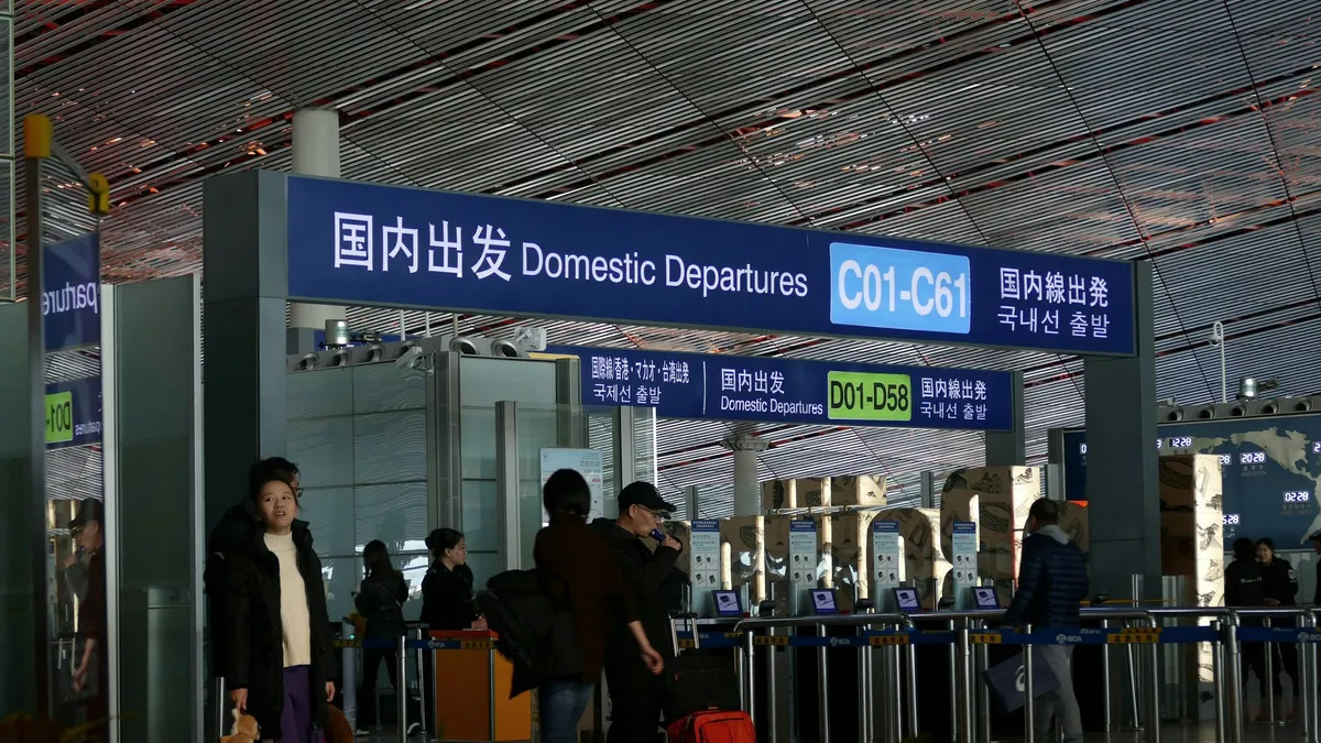 A bilingual Domestic Departures sign above check-in counters at a Chinese airport terminal