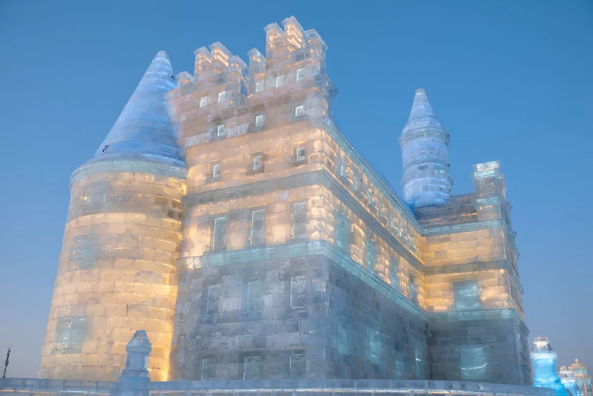 An illuminated ice castle at Harbin Ice and Snow World at dusk