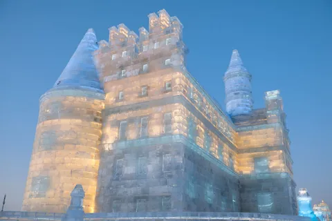 An illuminated ice castle at Harbin Ice and Snow World at dusk