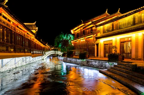 Lantern-lit canal and Naxi timber buildings in Lijiang Old Town at night