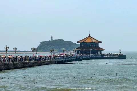 Crowds walking Zhanqiao Pier toward its double-roofed pavilion in Qingdao