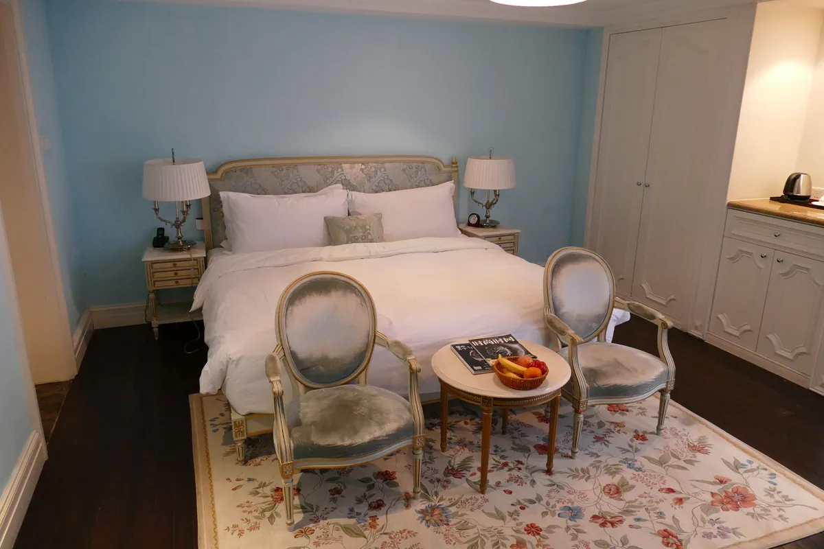 A comfortable hotel room in China with a made bed, seating area, and wardrobe