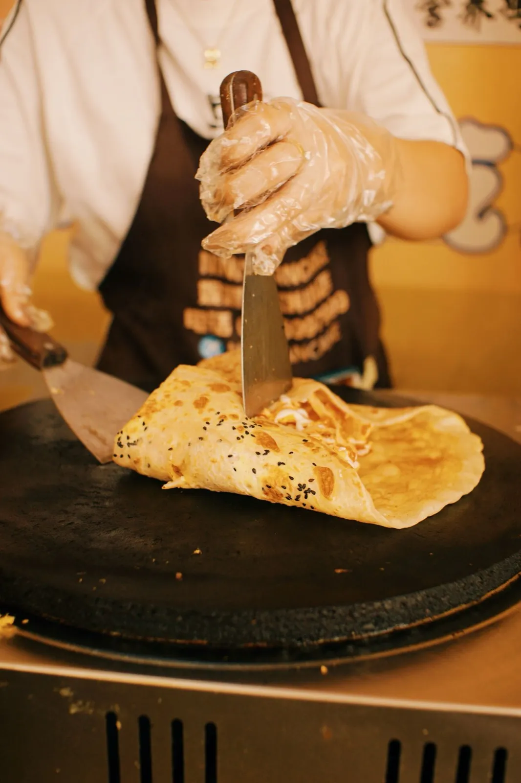 A vendor making jianbing, a Chinese savory crepe, at a street cart
