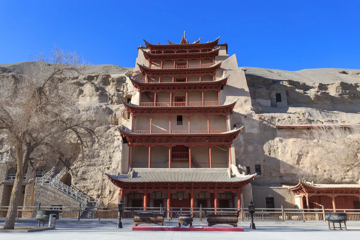 The multi-story red pagoda facade built over the giant Buddha cave at Mogao Caves