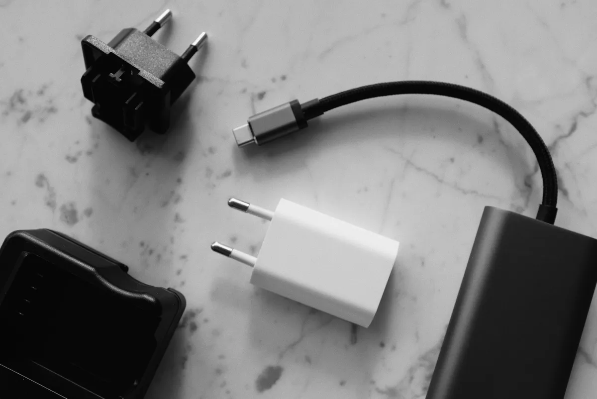 Travel chargers, a plug adapter, a power bank, and a short USB cable laid out on a table