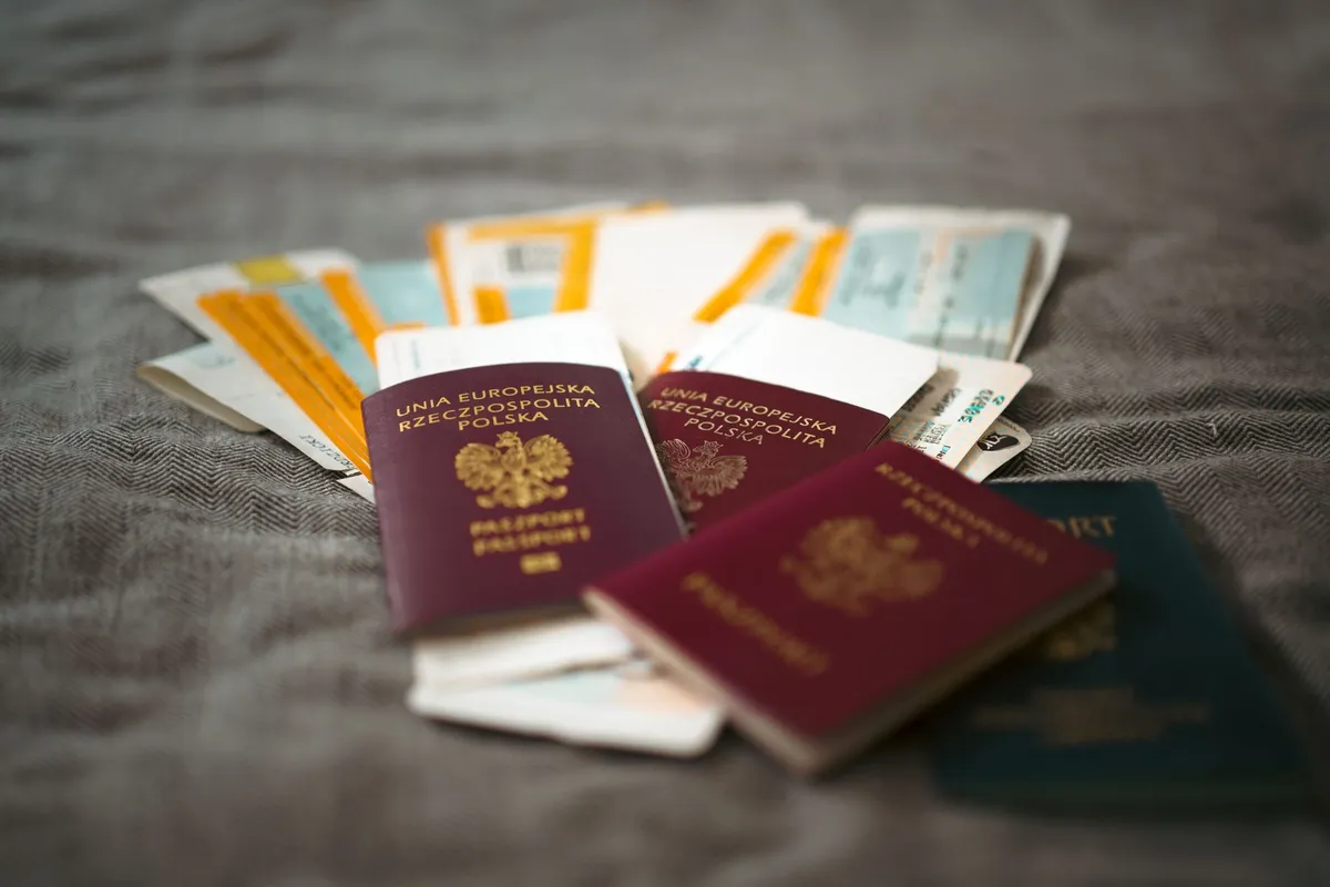Passports and travel tickets fanned out on a bed before a trip