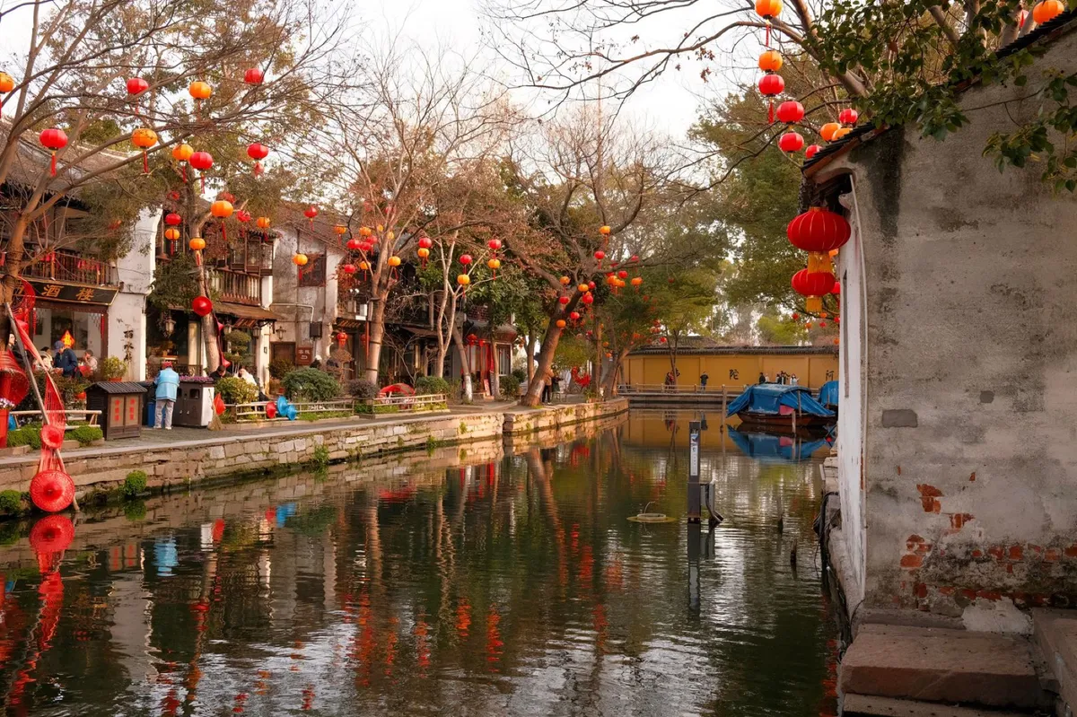 A canal lined with red lanterns and traditional buildings along Pingjiang Road in Suzhou