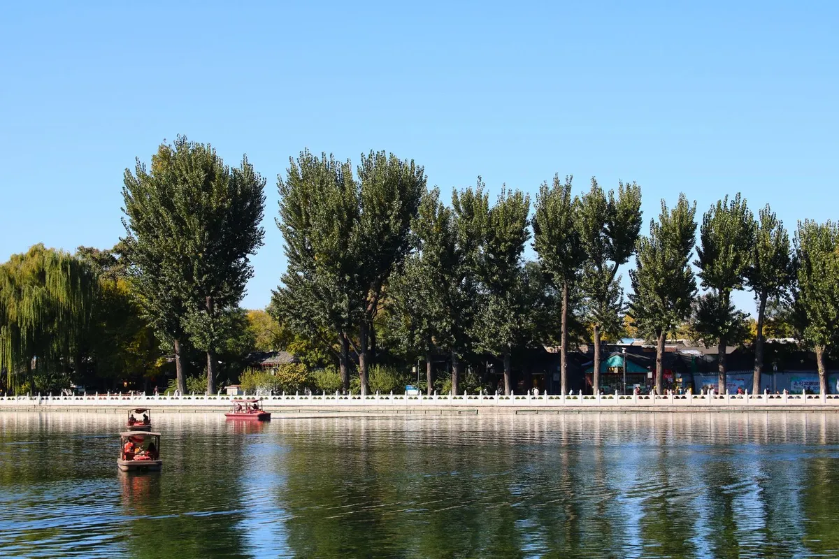 Pedal boats on Shichahai lake with willows and the white lakeside balustrade