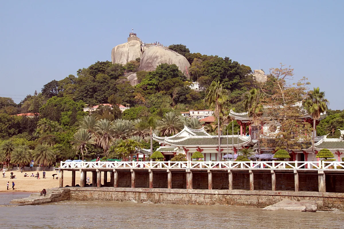 Sunlight Rock's granite summit rising above Gulangyu's palm trees and pavilions, seen from the waterfront