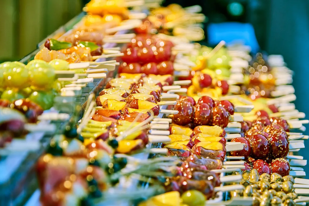 Rows of tanghulu — fruit skewers coated in hardened sugar syrup — on display at a street stall