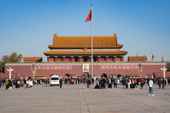 The Gate of Heavenly Peace at Tiananmen Square with the national flag and visiting crowds