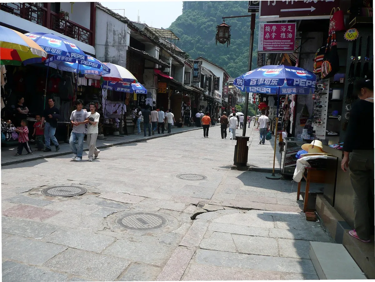 Shops and pedestrians along Yangshuo's West Street with a karst peak in the background